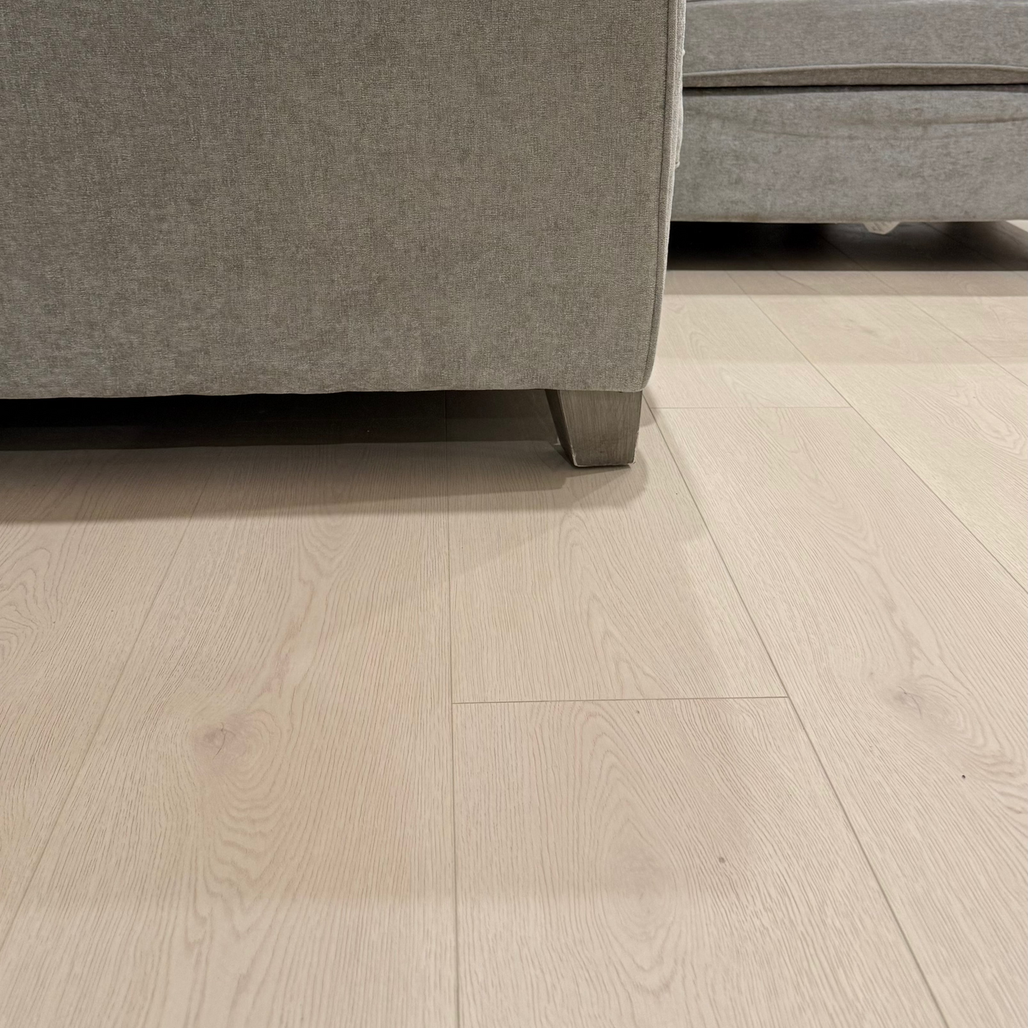 Close-up of a gray sofa corner on a light wood floor