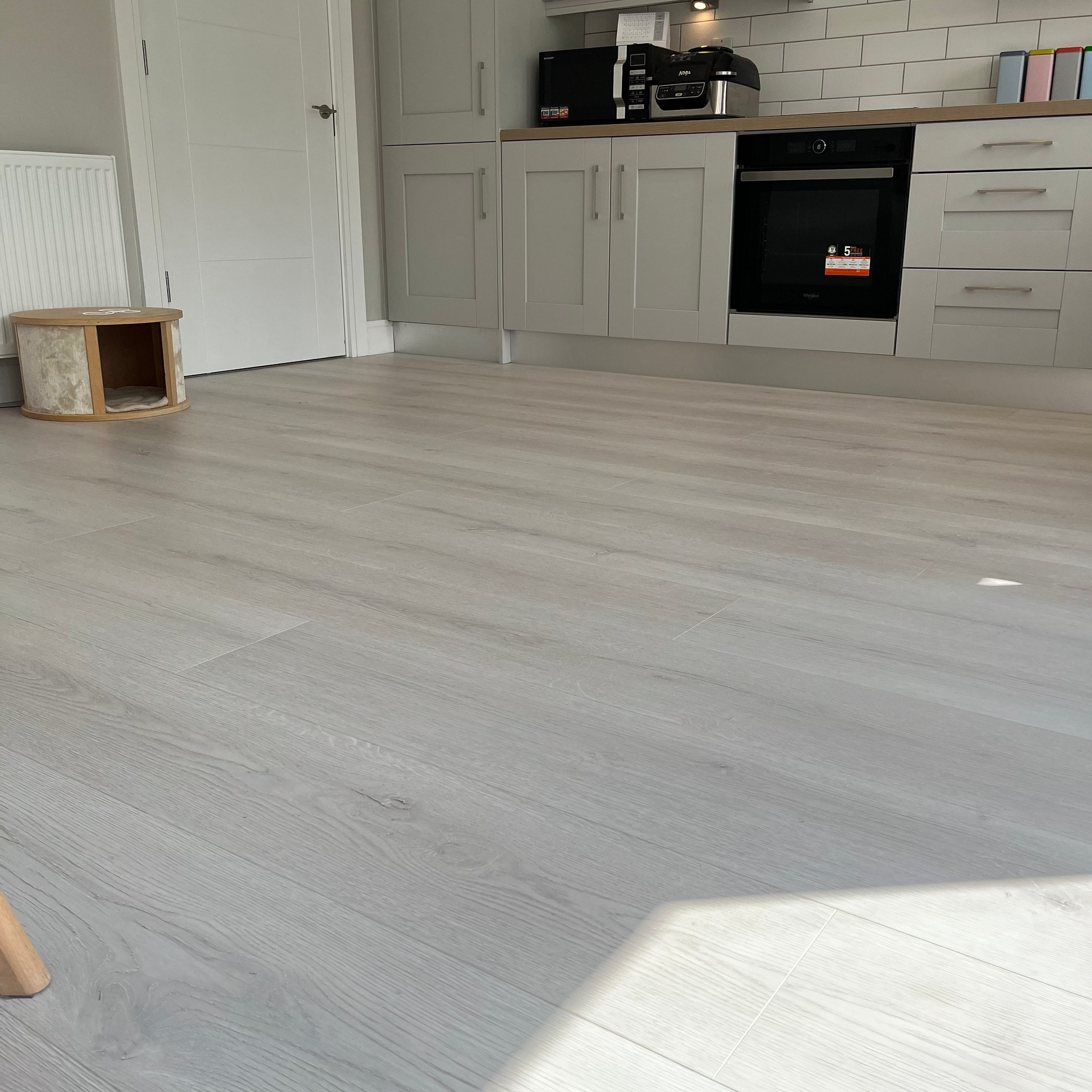Kitchen with gray wooden flooring and white cabinets.