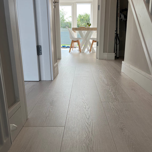 Interior hallway featuring long plank laminate flooring with a light oak finish, installed in a residential setting.