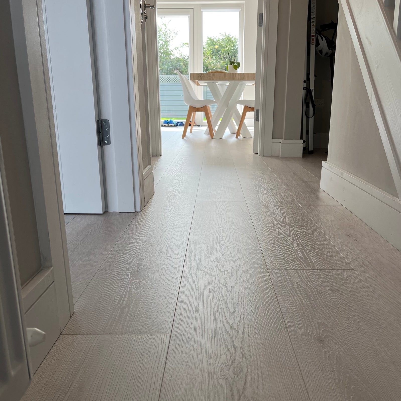 Interior hallway featuring long plank laminate flooring with a light oak finish, installed in a residential setting.