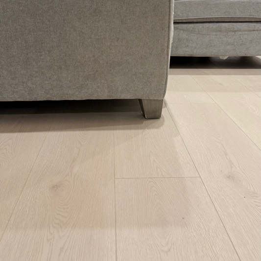 Close-up of a gray sofa corner on a light wood floor